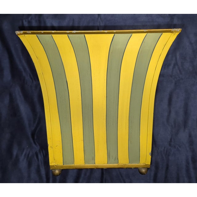 This is a vintage or decorative metal planter, cachepot, or magazine holder. It is positioned centrally against a dark,...