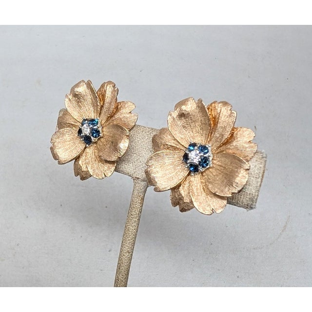 Circa late 1960s textured goldtone flower with single small clear round rhinestone in the center surrounded by small round...