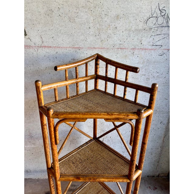 This vintage three-tier corner shelf is crafted in richly toned tiger rattan and dates to the 1950s, reflecting the...