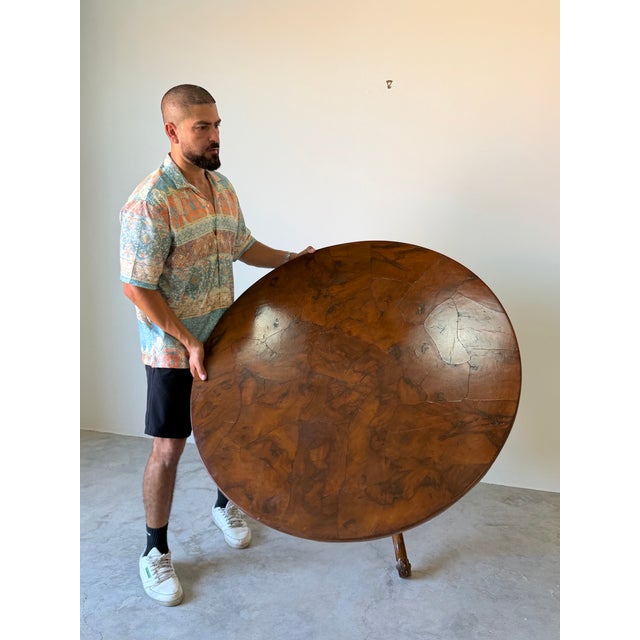 Elegant vintage English-style round dining table featuring a striking patchwork burl walnut veneer top, showcasing rich...