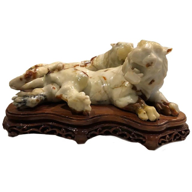 Two early 20th century white and russet stained white jade lions on a single custom wooden stand.