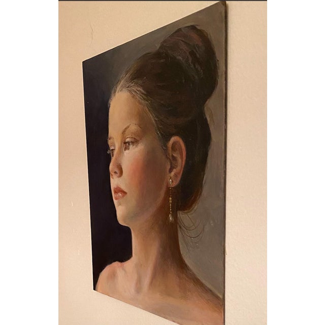 The painting captures a serene profile of a young woman, emphasizing her delicate features and thoughtful expression....