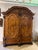 Walnut, veneered on oak. High, two-door body with panels and half-columns with carved capitals, on ball feet. Profiled...