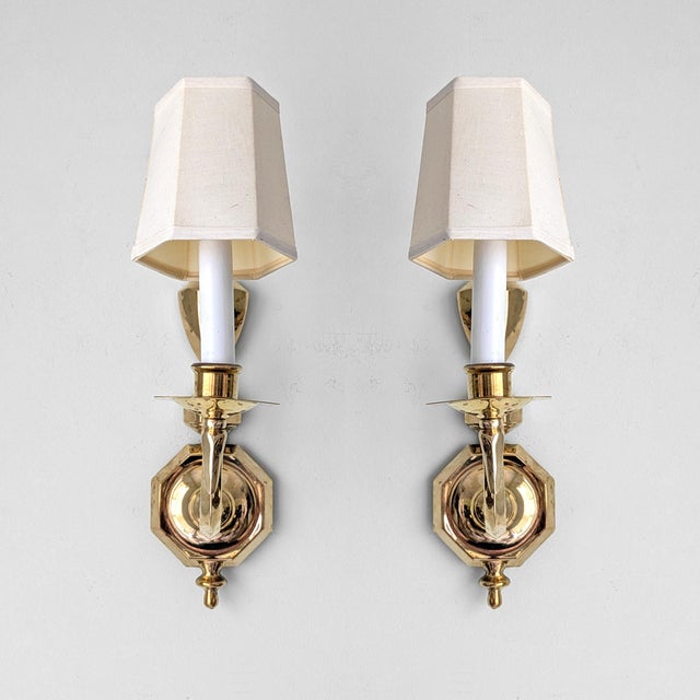 A pair of vintage French Provincial style wall sconces with polished brass design and candletick style light.