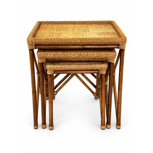 A charming set of three vintage bamboo and woven rattan nesting tables featuring warm, naturally aged finishes and classic...