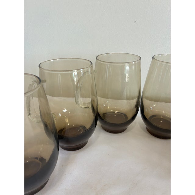 A set of six Libbey “Tempo” smoked glass mugs from the 1970s, showcasing the warm earth-tone aesthetic that defined the...