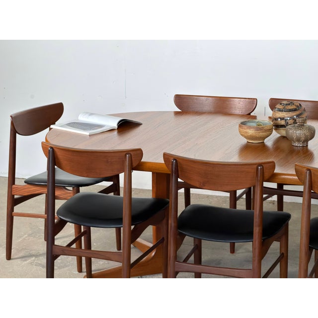 Danish set of eight dining chairs in teak, designed by Harry Østergaard, 1960s. Each chair pairs a crescent-shaped teak...