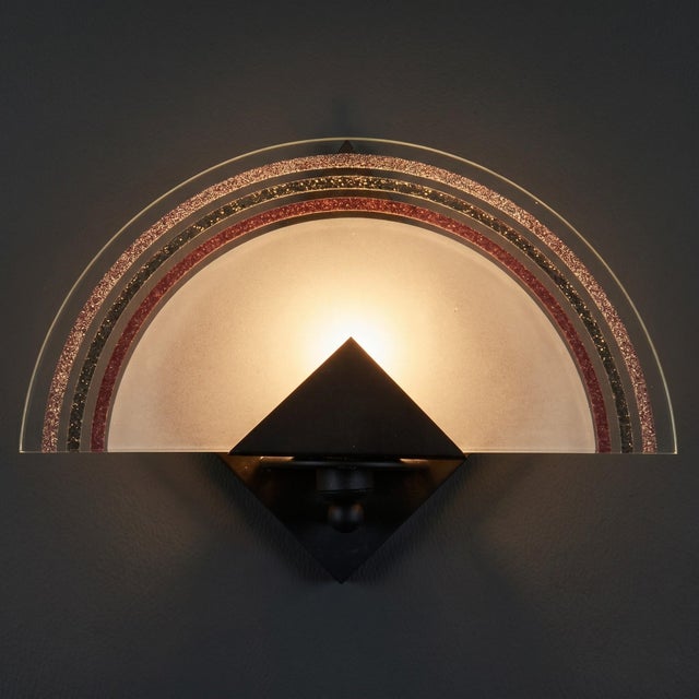 A sophisticated lighting element with a refined geometric design. This rare and valuable wall lamp represents a perfect...