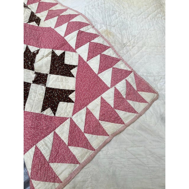 A single antique American patchwork quilt featuring a geometric pattern of hand stitched cotton fabric in pink, white, and...