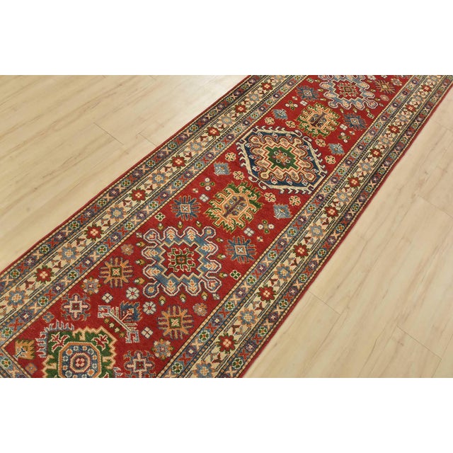 A tribal Caucasian Kazak runner hand-knotted with fine wool on a cotton foundation. This rug features a row of geometric...