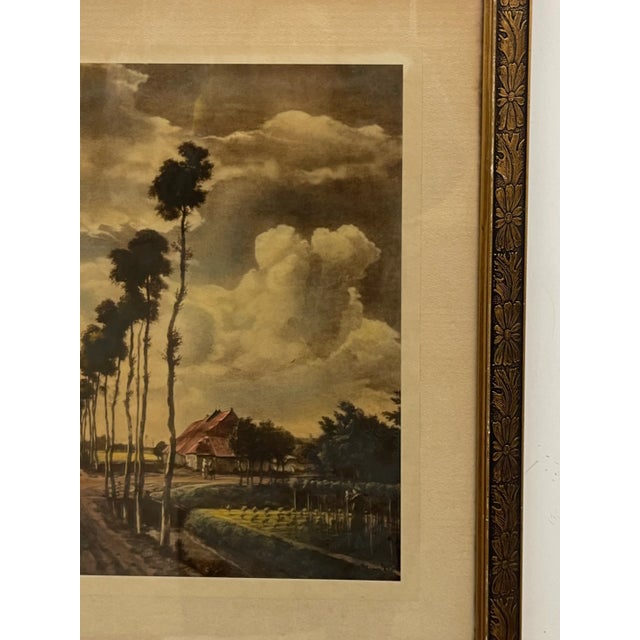 A framed landscape print depicting a serene rural scene with a long tree-lined dirt road stretching toward the horizon...
