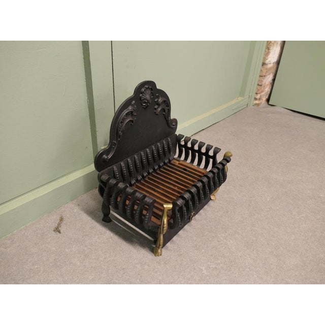 A Regency Style Iron Fire Grate The fire has a decorative high shaped back, in front of this there is an open fire basket...