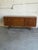 This architectural low sideboard features a minimal profile elevated by a sculpted four-legged trestle base. The...