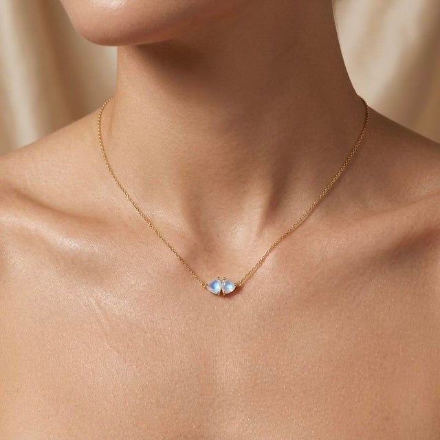 Enchant your style with this luminous two-stone pendant necklace, featuring two glowing, mystical heart-shaped gemstones...