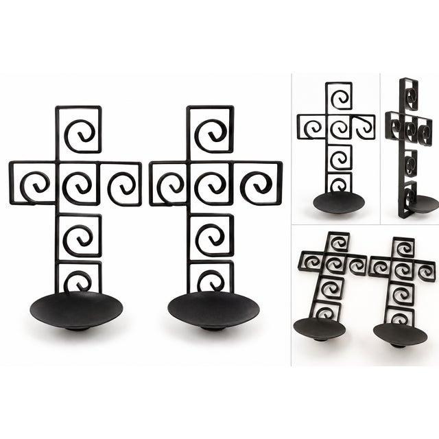 Elegant pair of black metal cross-shaped candle holders featuring beautiful geometric scrollwork and decorative spiral...