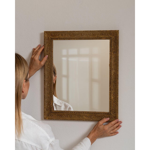 Carved giltwood mirror in Antique Gold. Its antique gold finish sets off rectangular molded frame, warm aged gilt, a...