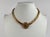 Signed Miriam Haskell gold-tone necklace featuring a wide curb-link gold tone chain and a centrally mounted Austrian coin-...