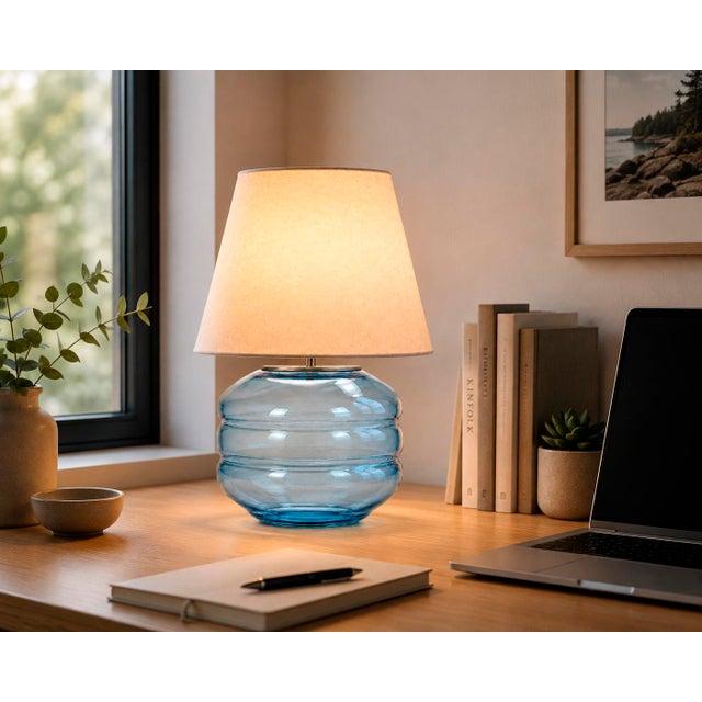 Crafted with high visual clarity, this modern table lamp features a sleek silhouette with a hand-blown glass base paired...