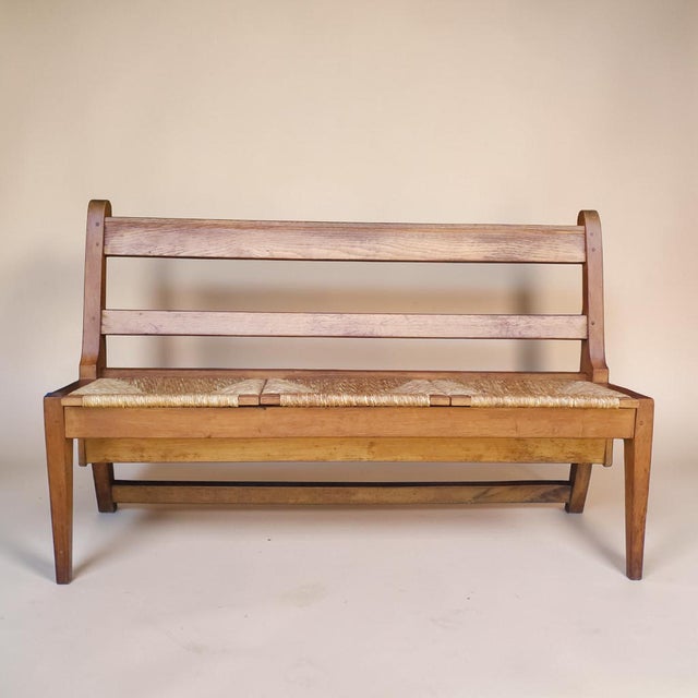 A striking mid-century oak hall bench with clean architectural lines and a handwoven rush seat, likely Dutch or...