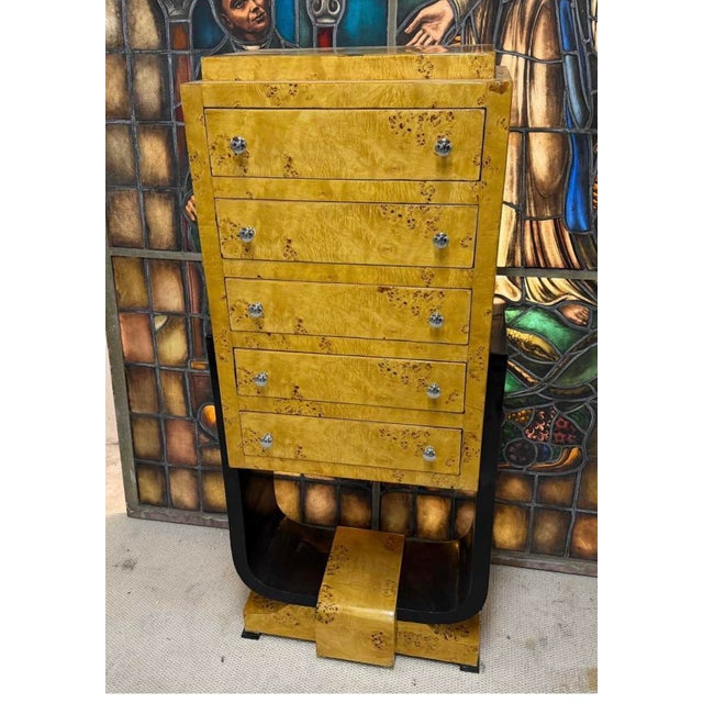 Striking five-drawer semainier chest finished in a warm golden burl/bird's-eye veneer with round chrome pulls. The chest...