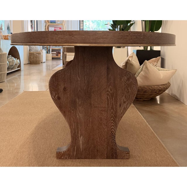 Contemporary organic dining table featuring a rich medium walnut-brown finish with a striking oval top and sculptural...