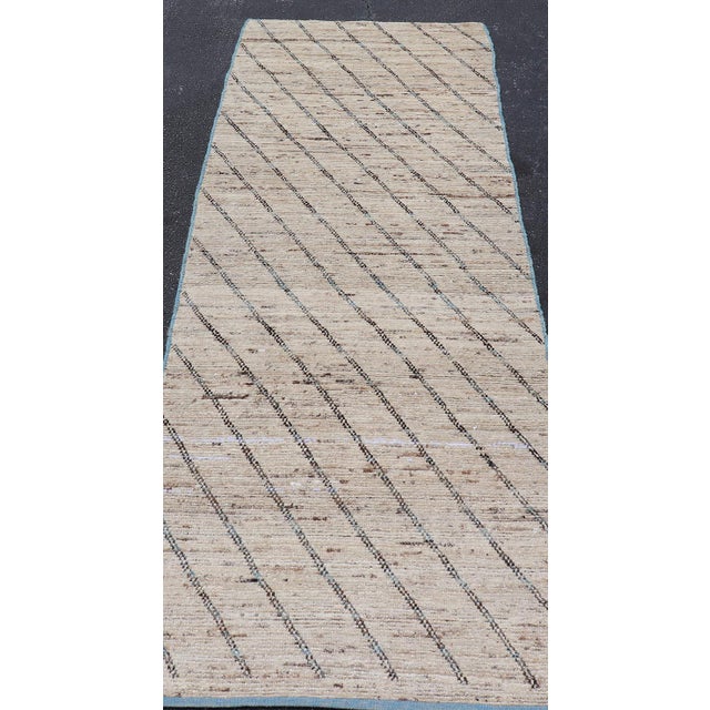 This modern casual tribal rug has been hand-knotted. The rug features a modern slanted linear design, rendered in neutral...