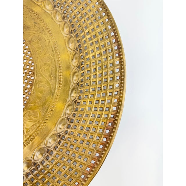 A striking vintage brass decorative tray featuring intricate pierced latticework and richly detailed ornamental borders....