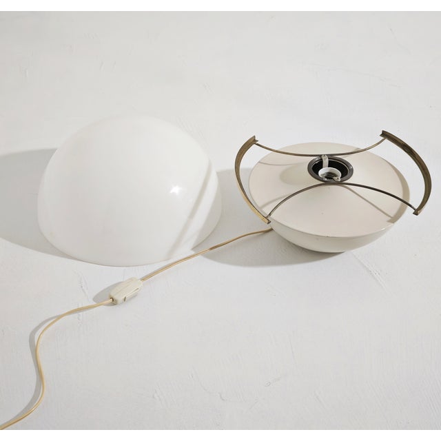 Table lamp made in Italy in the late 1960s. Ivory white aluminum body with a brass support structure and a hemispherical...