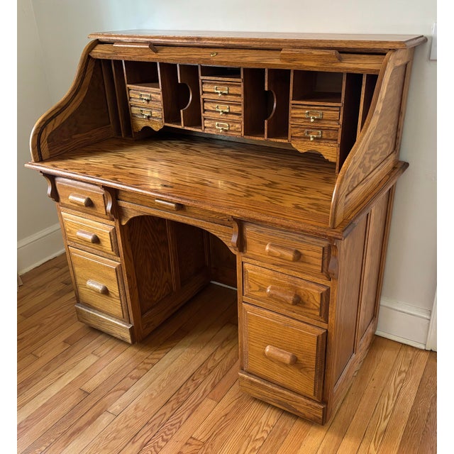 A finely crafted midcentury Arts & Crafts oak roll top desk, which features a raised panel design on sides and back with a...
