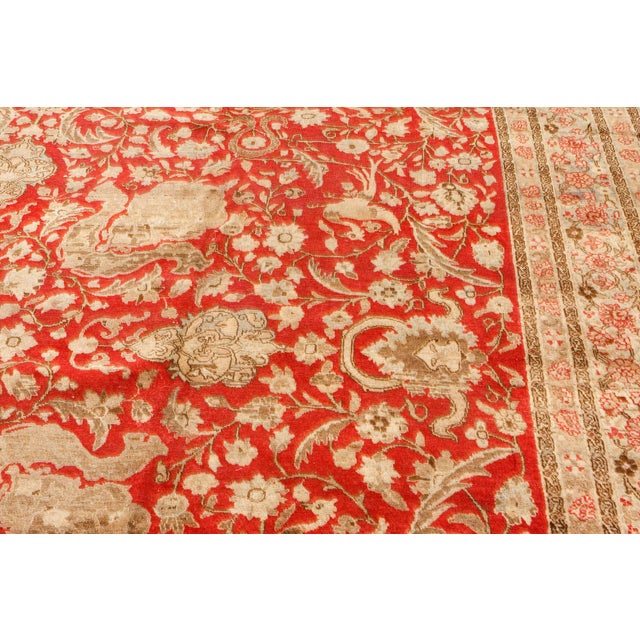 A decorative late 19th century Persian Tabriz carpet, the rich red field with whimsical swirling flowering vinery, exotic...