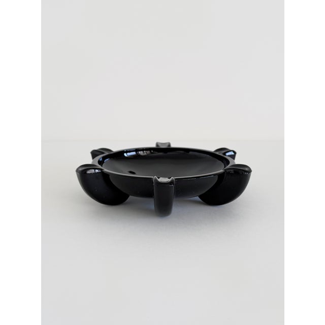 An opaque black glass ashtray in the Streamline Moderne style, dating to the 1940s. Cast in solid glass with a substantial...