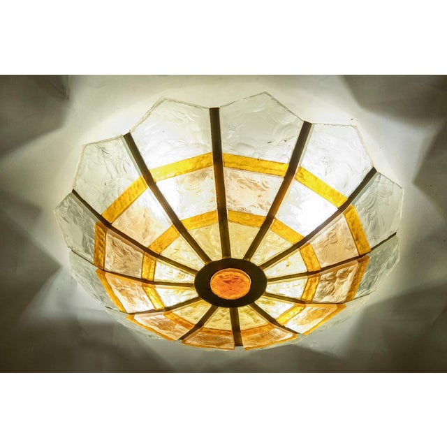 Brutalist-style glass and brass ceiling light, designed with a shell-like form. At the center stands a large red glass...