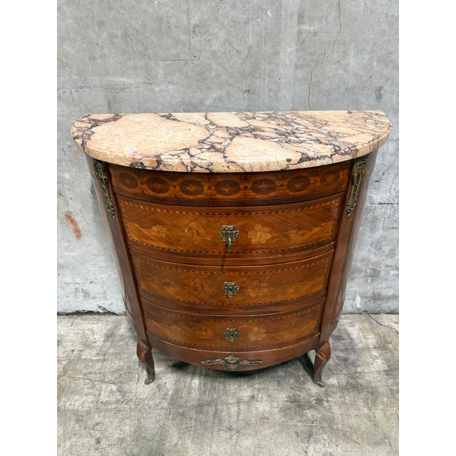 An elegant antique French marquetry commode featuring exquisite floral inlay, ormolu mounts, and a richly veined marble...