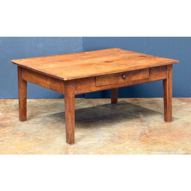 A large French cocktail or coffee (low) table of patinated cherry wood, featuring a handsome rectangular plank top set...