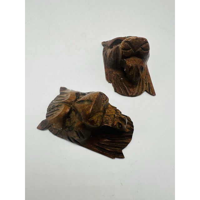 • The carvings depict stylized lion faces, each with a prominent brow, snout, and mane. • The features are symmetrical and...