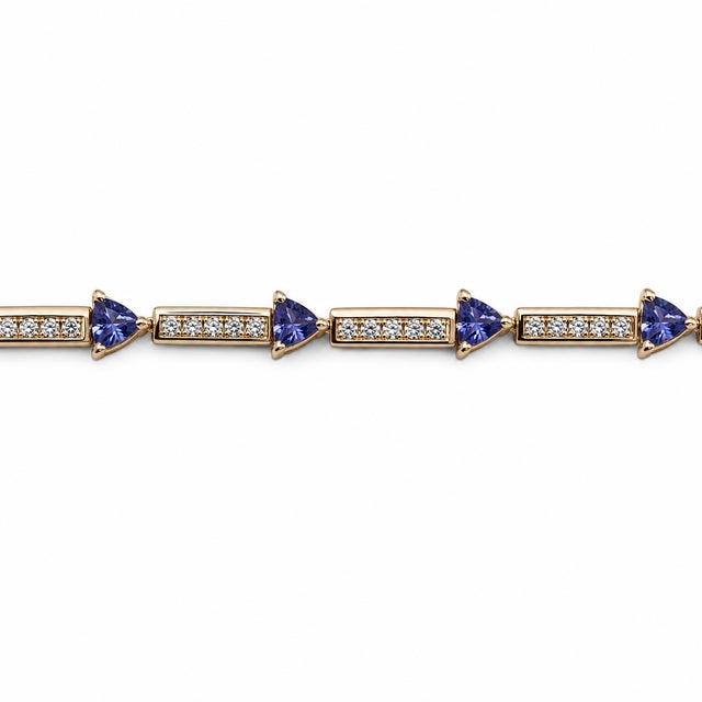 An elegant 14K yellow gold tennis bracelet featuring natural trillion-cut tanzanites accented by diamond-set links. The...