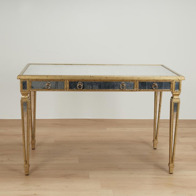 Striking vintage three drawer desk with brass hardware, crafted in hardwood in classic form, with a gold tone finish...