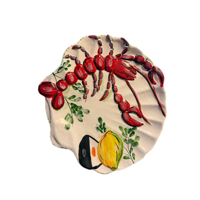 Vibrant majolica-style ceramic shell form platter featuring a bold red lobster paired with a bright yellow lemon and leafy...