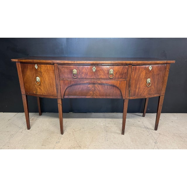 A Georgian period Sideboard dating to around 1800. Made from Mahogany and having 4 large drawers. Bow fronted, brass lions...