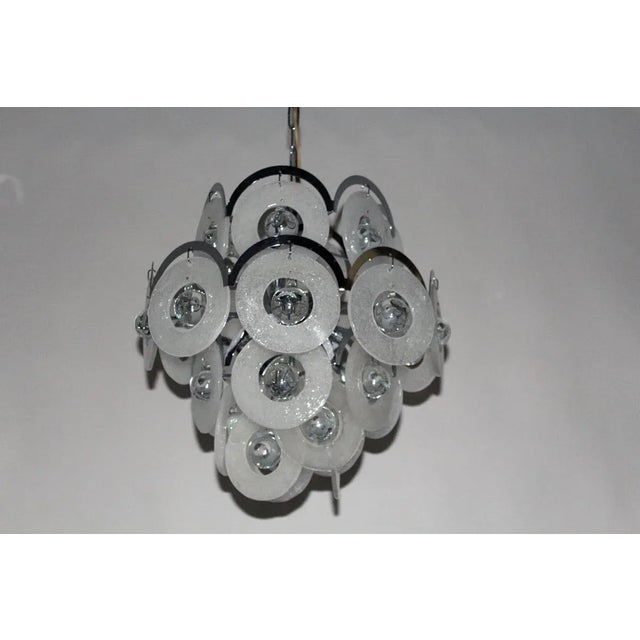 A very large Vistosi chandelier with 27 pieces of free-standing cast glass rings suspended from metal bows, into which a...