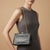 This is an elegant Italian shoulder bag from the 1950s, showcasing a luxurious combination of black leather and brass...