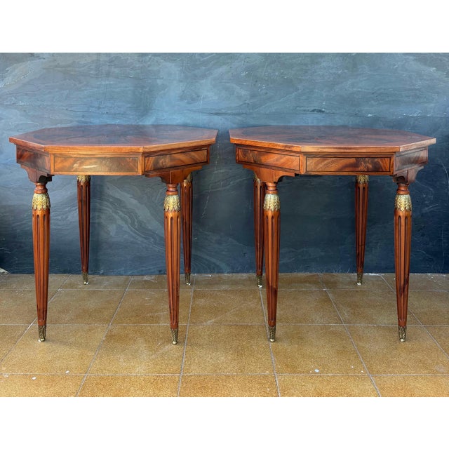 Each table features an octagonal top with a striking radial marquetry design framed by a contrasting border. The tapered...