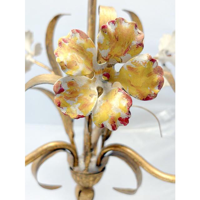 A whimsical vintage three-light chandelier with painted floral motifs. Three sculpted flowers, which are white with subtle...