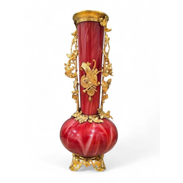 Elegant blown glass vase in a deep ruby red tone, adorned with finely detailed gilded metal mounts. A refined example of...