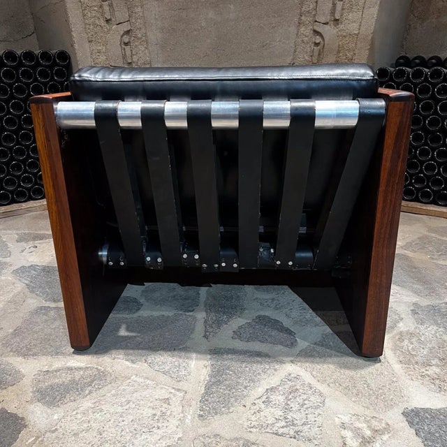 AMBIANIC presents Mid Century Modern Rosewood Club Chair. Elegant wood grain. New cushion in black Faux Leather. Aluminum...