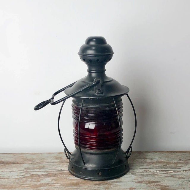 A pair of tole and red glass ship's lanterns, circa 1900.