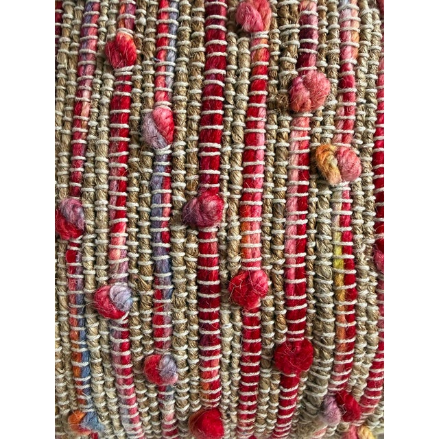 Beautiful woven soft natural jute pillow with pinks and purple wool tie pom-pom knots. Cotton fill with zipper and off-...