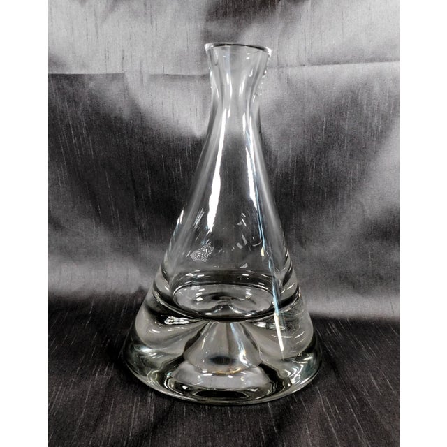 This is a large crystal decanter that is shaped like a cone. It has a solid two inch thick base with a bubble in it and a...