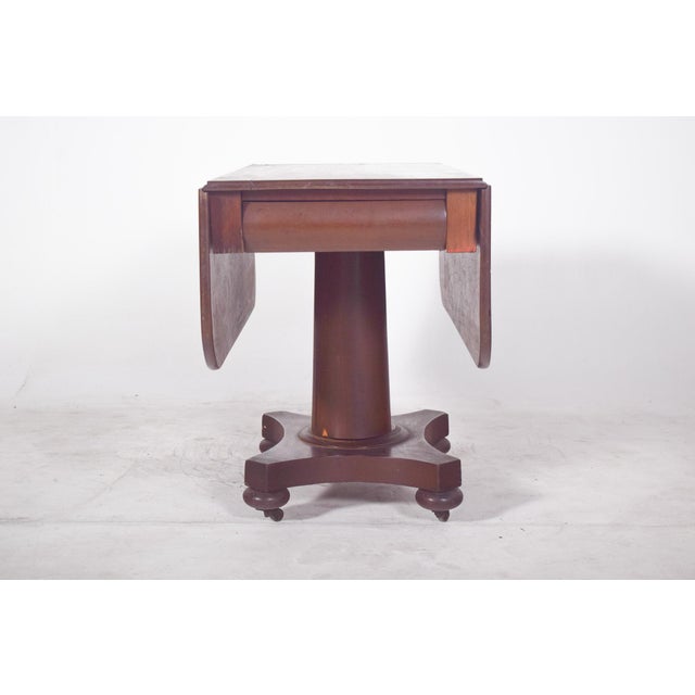 Flap table with central foot. The base is cross shaped with softly spherical wooden castors complementing the design with...