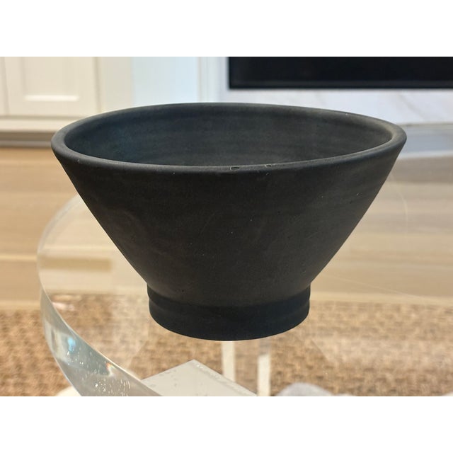 Hand thrown studio pottery bowl in a deep charcoal black matte finish on raised foot with subtle concentric throwing marks...